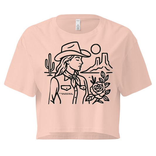Pale Pink crop top with graphic of a cowgirl, desert landscape, sun, cacti, and rose #palepink