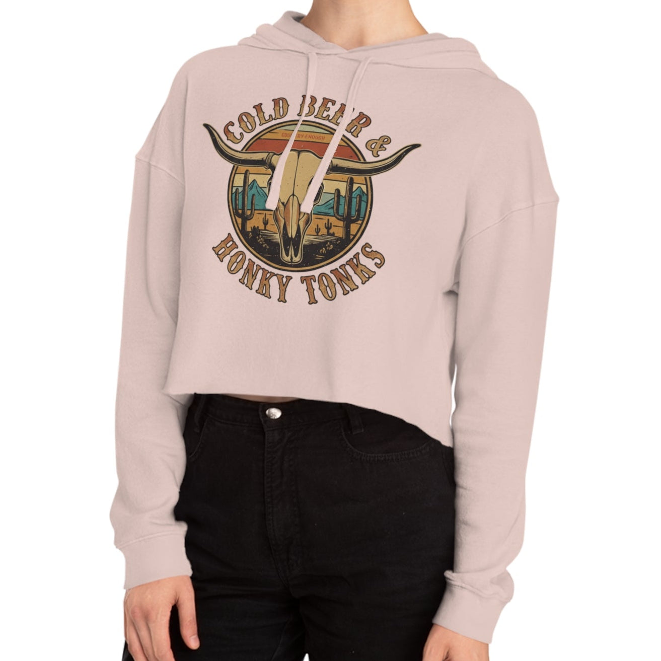 Pale Pink crop hoodie with graphic of longhorn, cacti, and mountains over a retro background with words cold beer and honky tonks #palepink