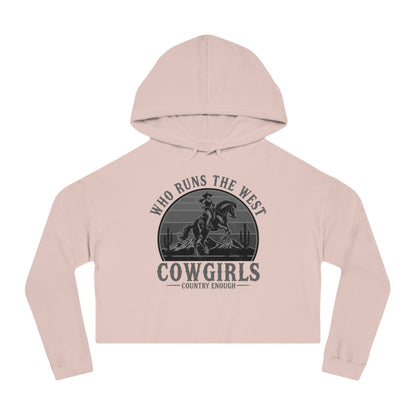 Pale Pink crop hoodie with graphic of a cowgirls on a bucking horse, cacti, mountains, and the words who runs the west cowgirls #palepink