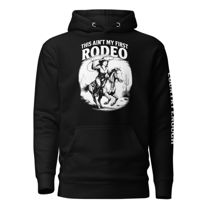 Black hoodie with graphic of cowgirl and horse, western landscape, and words this ain't my first rodeo #black