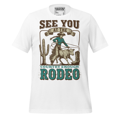 White t-shirt with graphic of cowgirl, calf, cactus, cowboy boot, and words see you at the rodeo #white