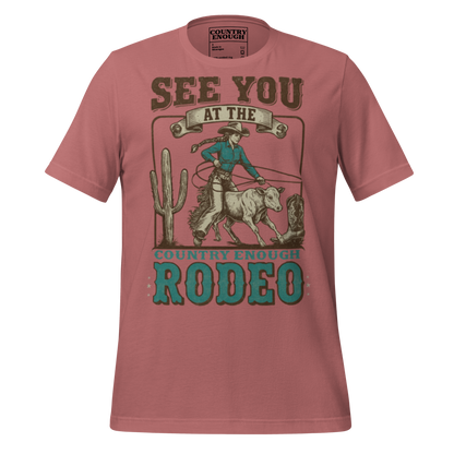 Mauve t-shirt with graphic of cowgirl, calf, cactus, cowboy boot, and words see you at the rodeo #mauve
