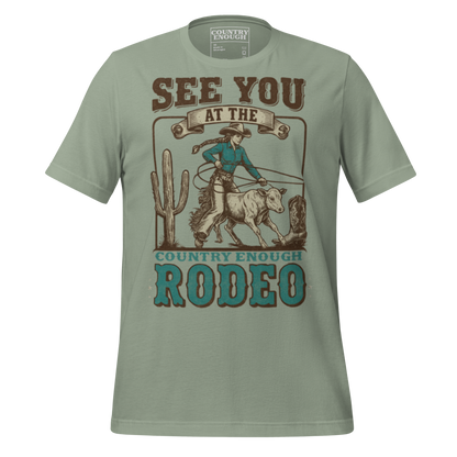 Sage t-shirt with graphic of cowgirl, calf, cactus, cowboy boot, and words see you at the rodeo #sage