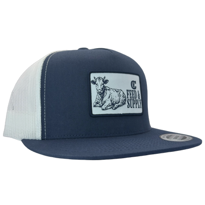 Yupoong 6006 snapback hat with patch that contains graphic of a sitting cow, the words Feed & Supply, and the CE logo. #navy/white