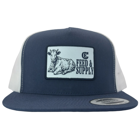 Yupoong 6006 snapback hat with patch that contains graphic of a sitting cow, the words Feed & Supply, and the CE logo. #navy/white
