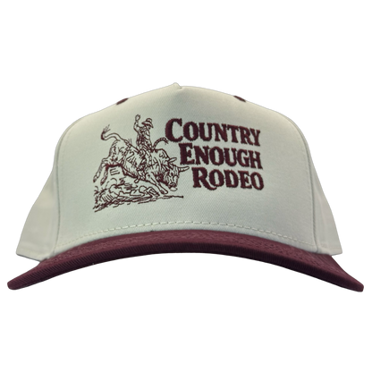 Legacy heritage snapback hat with graphic of bull rider on a bucking bull and the words country enough rodeo #wine