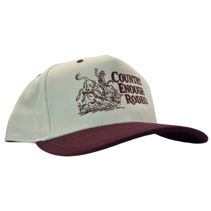 Legacy heritage snapback hat with graphic of bull rider on a bucking bull and the words country enough rodeo #wine
