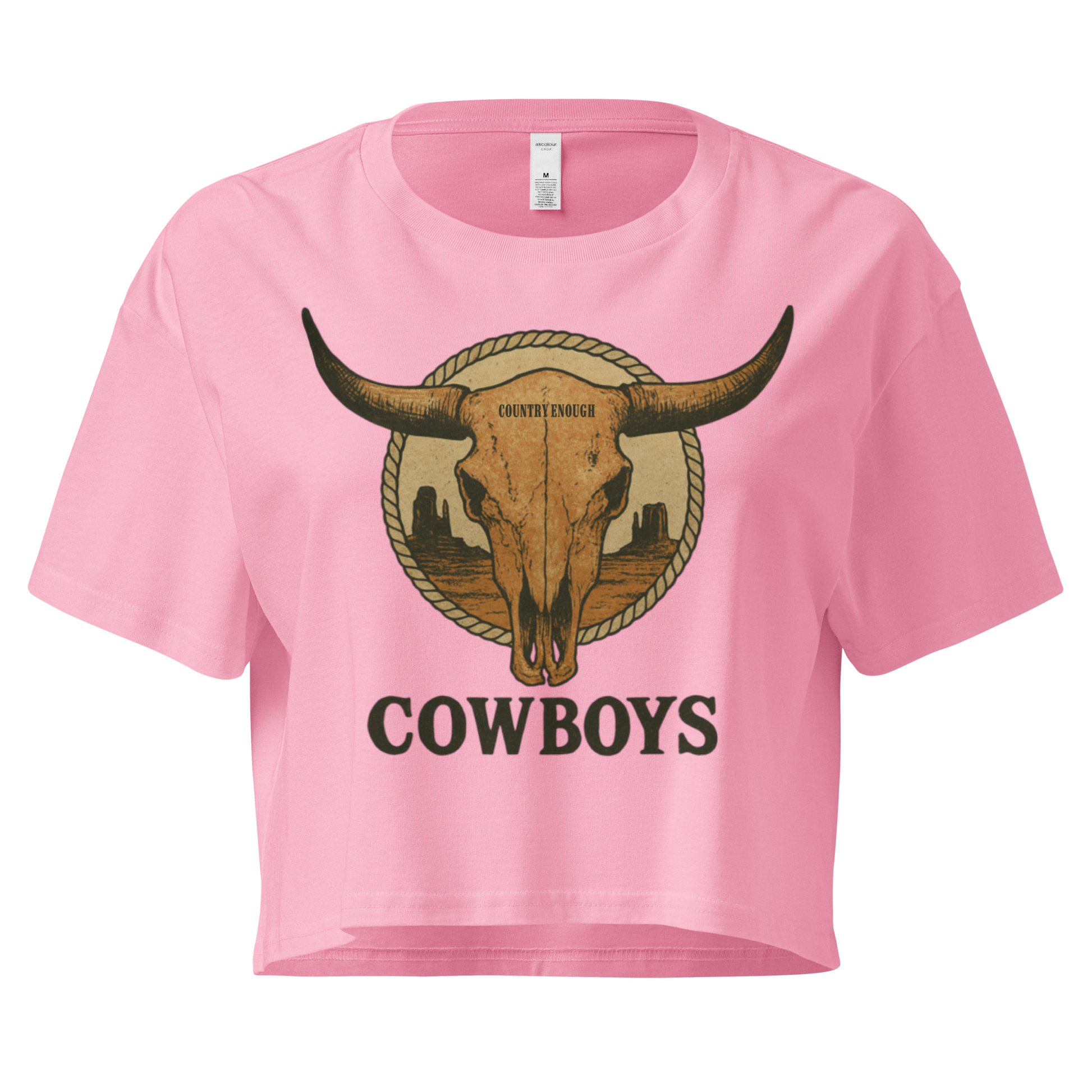 Pink crop top with graphic of bull skull in front of a circular desert landscape with rope border and word cowboy below #pink