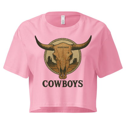 Pink crop top with graphic of bull skull in front of a circular desert landscape with rope border and word cowboy below #pink