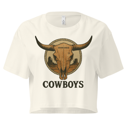 Natural crop top with graphic of bull skull in front of a circular desert landscape with rope border and word cowboy below #natural