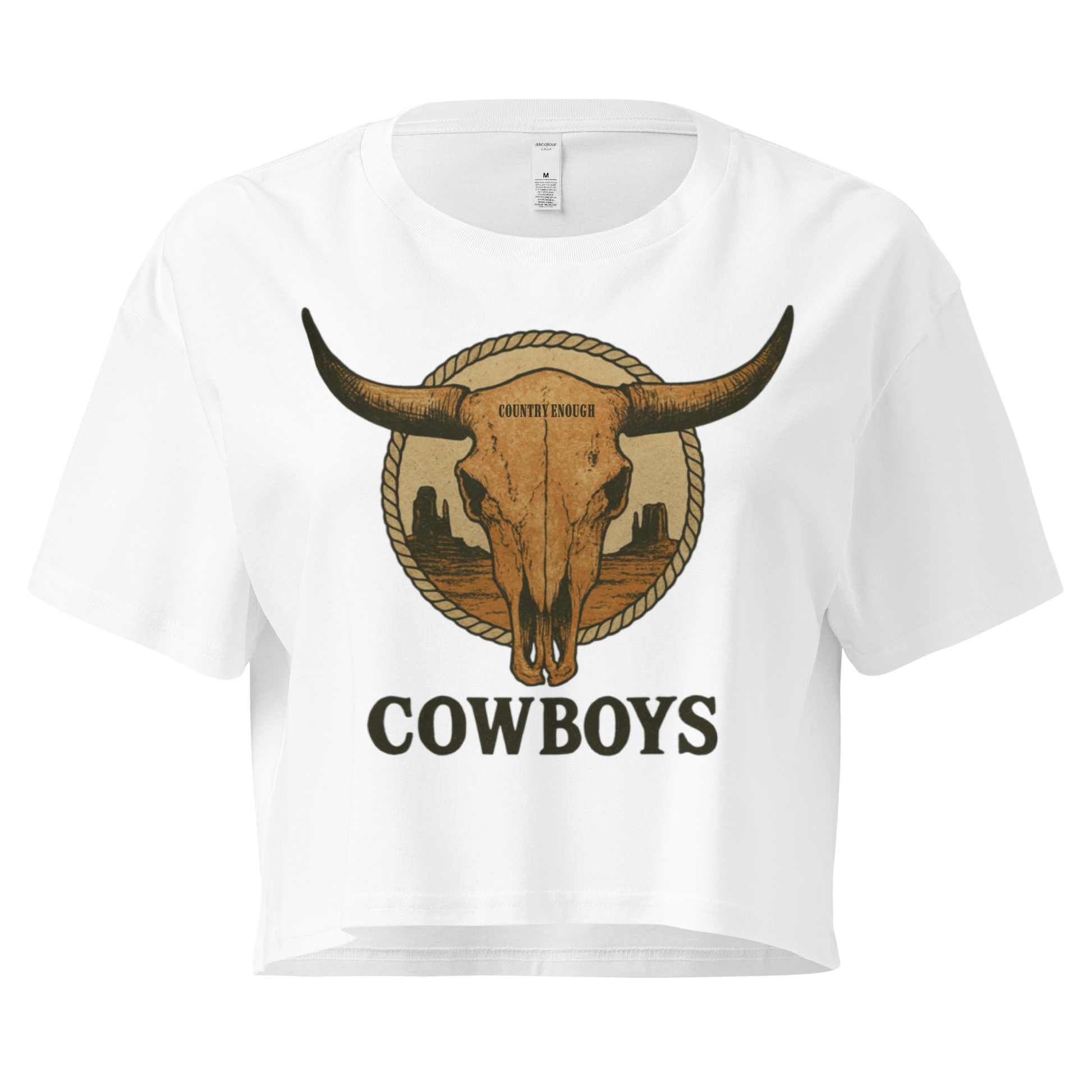 White crop top with graphic of bull skull in front of a circular desert landscape with rope border and word cowboy below #white
