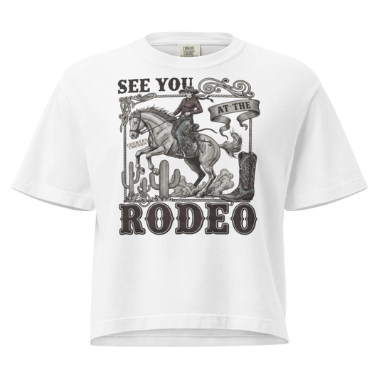 White t-shirt with graphic of cowgirl, cowboy boot, cacti, horse, and words see you at the rodeo #white