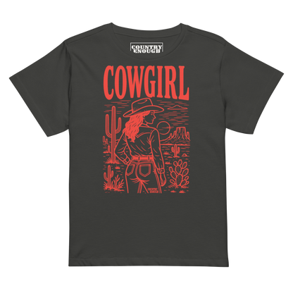 Vintage Black t-shirt of cowgirl standing in a desert scene with words cowgirl. all in bright red coloring #vintageblack