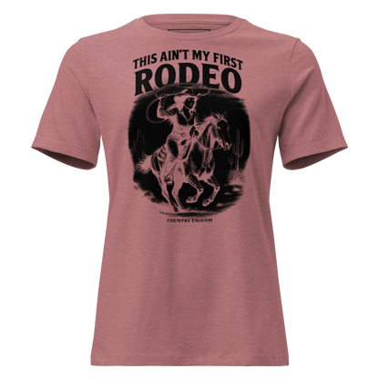 Heather Mauve t-shirt with graphic of a cowgirl on a horse, lassoing, in front of a desert landscape with words this ain't my first rodeo above #heathermauve