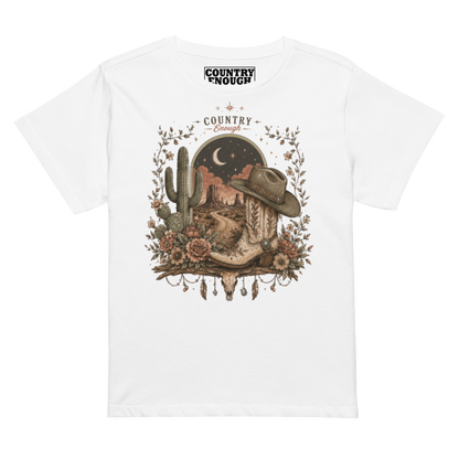 Women's t-shirt with graphic of bull skull, cowboy boot, cowboy hat, desert landscape and night sky. #white