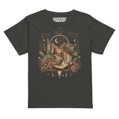 Women's t-shirt with graphic of bull skull, cowboy boot, cowboy hat, desert landscape and night sky. #vintageblack