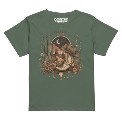 Women's t-shirt with graphic of bull skull, cowboy boot, cowboy hat, desert landscape and night sky. #pine